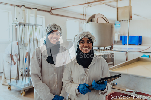 Image of Arab business partners checking the quality of cheese in the industry and enter data into a laptop. Small business concept