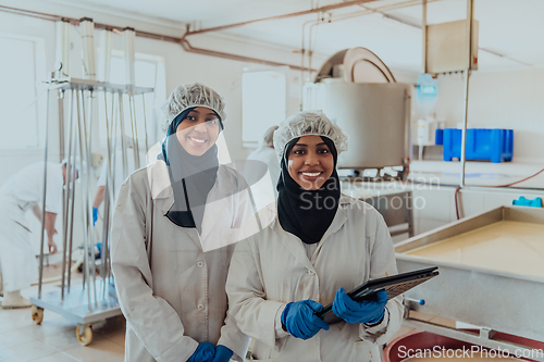 Image of Arab business partners checking the quality of cheese in the industry and enter data into a laptop. Small business concept