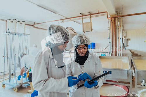 Image of Arab business partners checking the quality of cheese in the industry and enter data into a laptop. Small business concept