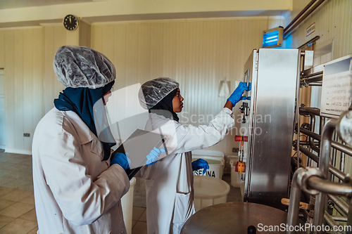 Image of Arab business partners checking the quality of cheese in the industry and enter data into a laptop. Small business concept