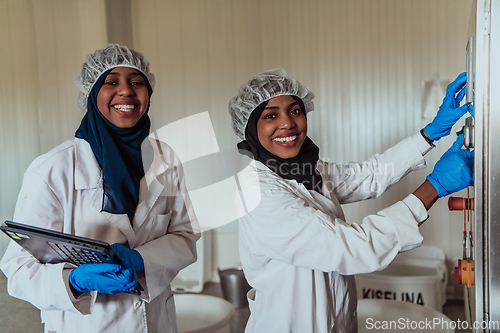 Image of Arab business partners checking the quality of cheese in the industry and enter data into a laptop. Small business concept