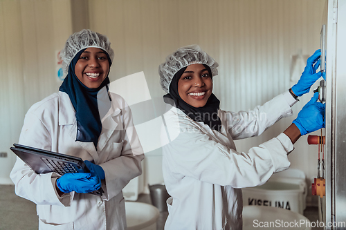 Image of Arab business partners checking the quality of cheese in the industry and enter data into a laptop. Small business concept