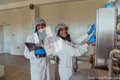 Image of Arab business partners checking the quality of cheese in the industry and enter data into a laptop. Small business concept