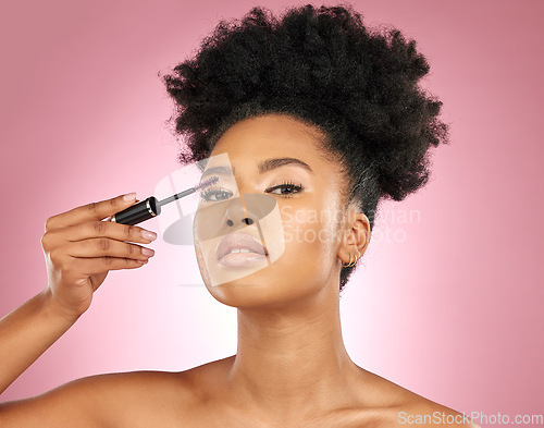 Image of Mascara, makeup and beauty portrait of a woman for skincare, wellness and dermatology glow. Volume, eyelash and face cosmetics of a black female model with facial shine on a pink background in studio