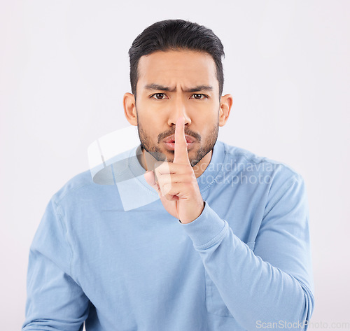 Image of Whisper, portrait and angry asian man in studio with finger on lips, sign and body language on grey background. Gossip, secret and face of annoyed Japanese male with confidential, privacy or emoji