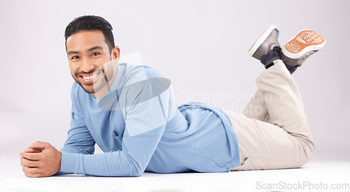 Image of Fashion, portrait and happy man on the floor in studio isolated on a white background. Style, smile and Asian person from Cambodia in casual clothes, trendy aesthetic or confidence to relax on ground