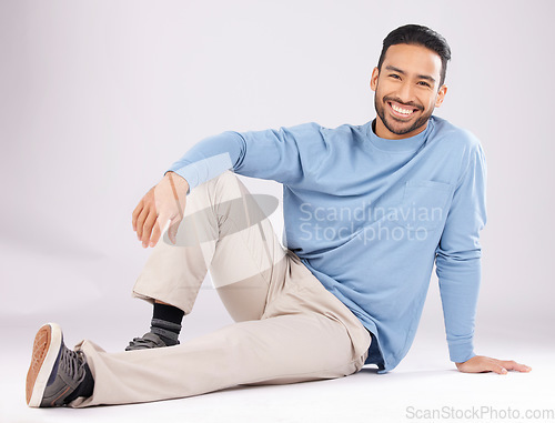 Image of Portrait, fashion and happy man on the floor in studio isolated on a white background. Style, smile and Asian person from Cambodia in casual clothes, trendy aesthetic or confidence to relax on ground