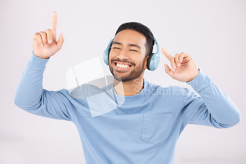 Image of Headphones, energy and man doing a dance in a studio with music, album or playlist with technology. Happy, smile and Indian young male model dancing to song or radio isolated by a white background.