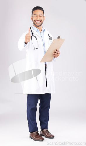 Image of Asian man, doctor and portrait with thumbs up for healthcare approval against a white studio background. Happy male person or medical expert smile with clipboard, like emoji or yes sign for success