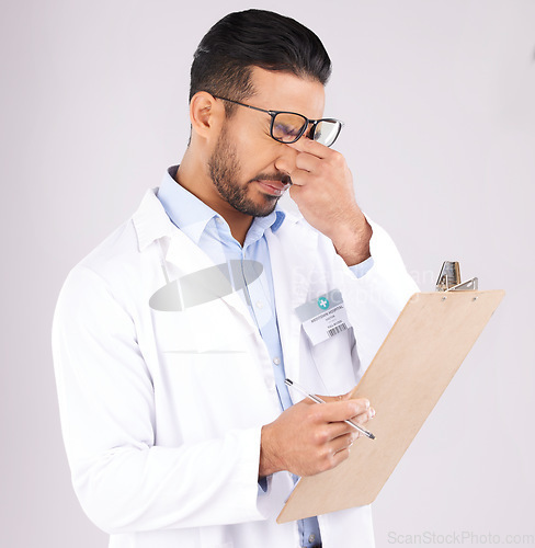 Image of Stress, checklist and man doctor in a studio for a medical diagnosis or wellness treatment. Burnout, headache and male healthcare worker with a migraine for clipboard isolated by a gray background.