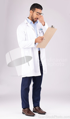 Image of Burnout, clipboard and man doctor in a studio for a medical diagnosis or wellness treatment. Stress, headache and male healthcare worker with a migraine for checklist isolated by a gray background.