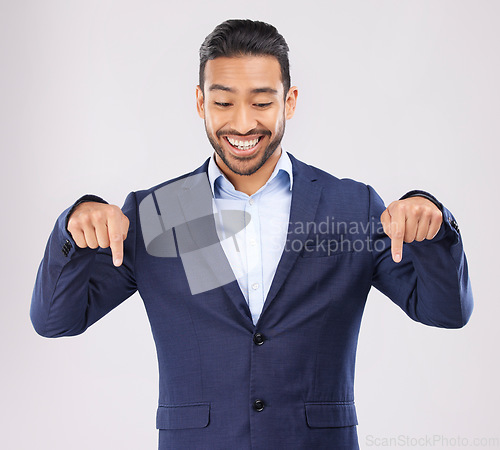 Image of Down, hand pointing and asian man in studio with sale, announcement or coming soon promo on grey background. Smile, news and Japanese male show launch, platform and giveaway, process or contact info