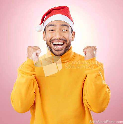 Image of Portrait, excited and smile, man with Christmas hat for fun and yes at festive holiday on pink background. Happy, winning celebration and model with santa cap and winter vacation success in studio.