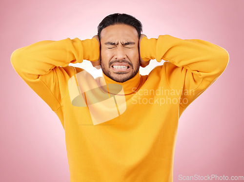 Image of Man, headache and cover ears for stress or mental health of student frustrated on a pink background. Angry, anxiety and fear or scared young person with hands to stop noise or sound in studio