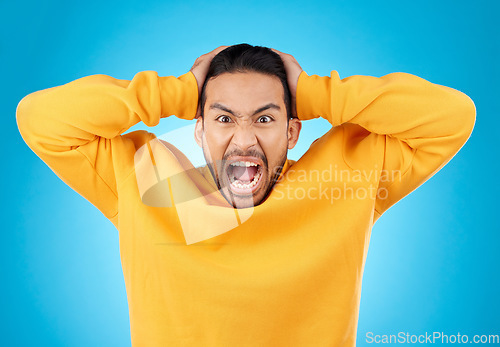 Image of Angry, man and portrait with screaming in studio with burnout, anxiety and stress. Mental health, blue background and frustrated male person with yelling with anger about problem, mistake and issue