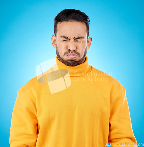 Image of Face, asian man and holding breath in studio for suspense, fear or stress on blue background. Puff cheeks, air and waiting to breathe by funny male person with countdown, nervous or uncertain emoji