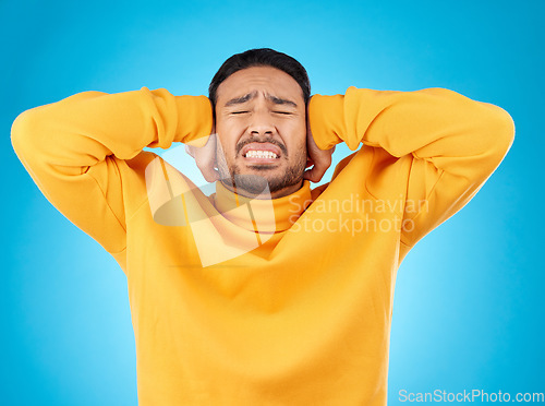 Image of Stress, headache and hands on ears of man in studio with noise, complaint or crisis on blue background. Anxiety, migraine and frustrated male with vertigo, brain fog or tinnitus, depression or trauma
