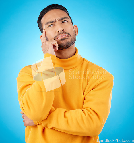 Image of Thinking, idea and young man in a studio with doubt, confused or choice facial expression. Problem solving, dream and Indian male model brainstorming, question or planning isolated by blue background