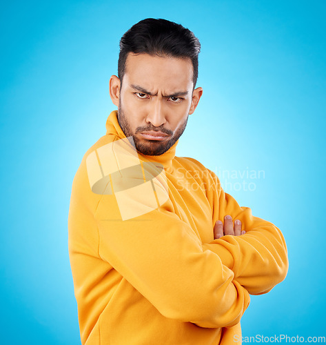 Image of Portrait, frown and asian man with arms crossed in studio angry, frustrated and annoyed on blue background. Conflict, anger and face of Japanese male with defensive body language, denial or offended