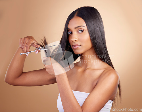 Image of Hair, portrait and Indian woman with scissors in studio for self haircut or trim on brown background. Haircare, face and female model with beauty tool for healthy growth, styling or cutting tips