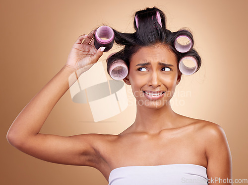 Image of Hair care, problem and a woman with rollers on a studio background for fail of curls. Sad, beauty and a young Indian model or girl with gear for a curly hairstyle mistake isolated on a backdrop