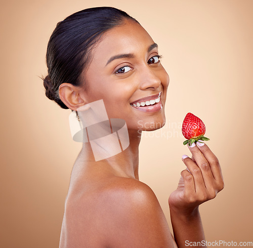 Image of Portrait, woman with a strawberry and skincare with natural beauty in studio or benefits in healthy nutrition, diet or fruit. Girl, eating or food with vitamin c for skin to glow or wellness of body