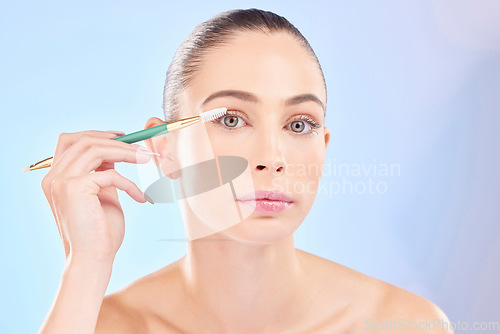 Image of Makeup, portrait and woman with brush on eyes on blue background for cosmetics and skincare. Mascara tools, eyelash and natural beauty, face of model with eye product application on lashes in studio.