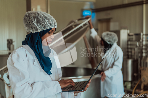 Image of Arab business partners checking the quality of cheese in the industry and enter data into a laptop. Small business concept