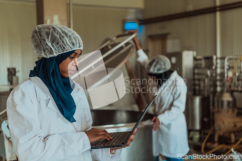 Image of Arab business partners checking the quality of cheese in the industry and enter data into a laptop. Small business concept