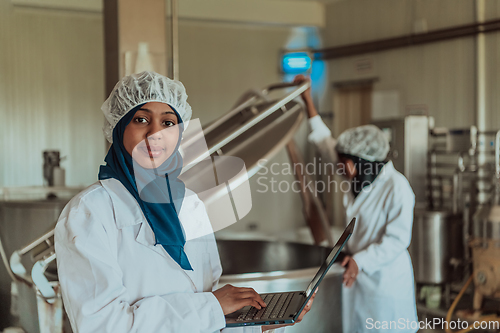 Image of Arab business partners checking the quality of cheese in the industry and enter data into a laptop. Small business concept