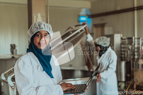 Image of Arab business partners checking the quality of cheese in the industry and enter data into a laptop. Small business concept