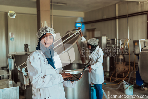 Image of Arab business partners checking the quality of cheese in the industry and enter data into a laptop. Small business concept