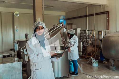 Image of Arab business partners checking the quality of cheese in the industry and enter data into a laptop. Small business concept