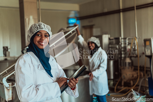 Image of Arab business partners checking the quality of cheese in the industry and enter data into a laptop. Small business concept