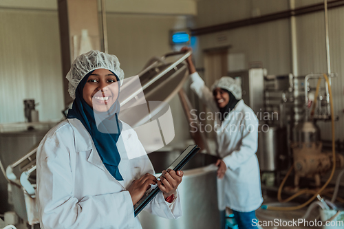 Image of Arab business partners checking the quality of cheese in the industry and enter data into a laptop. Small business concept