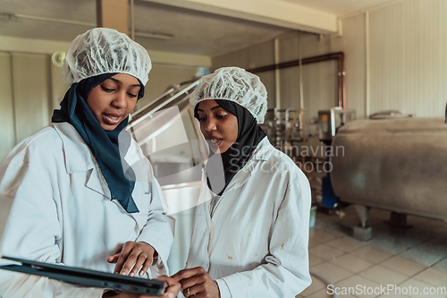 Image of Arab business partners checking the quality of cheese in the industry and enter data into a laptop. Small business concept