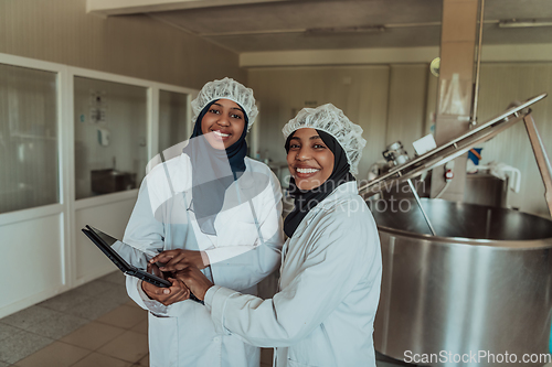 Image of Arab business partners checking the quality of cheese in the industry and enter data into a laptop. Small business concept