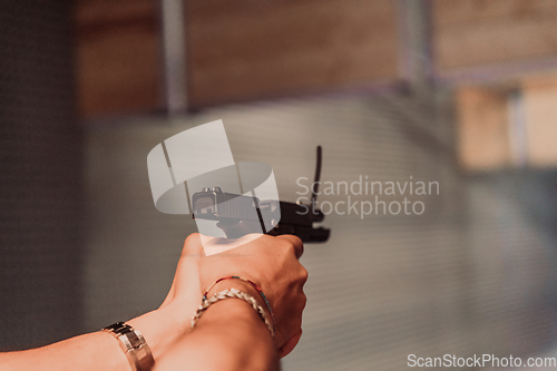 Image of A man practices shooting a pistol in a shooting range while wearing protective headphones