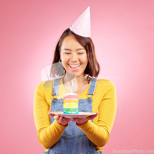 Image of Birthday cake candle, studio and happy Asian woman excited, smile and celebrate party, present or gift. Congratulations, wow and Japanese person with dessert, candy or sweets on pink background