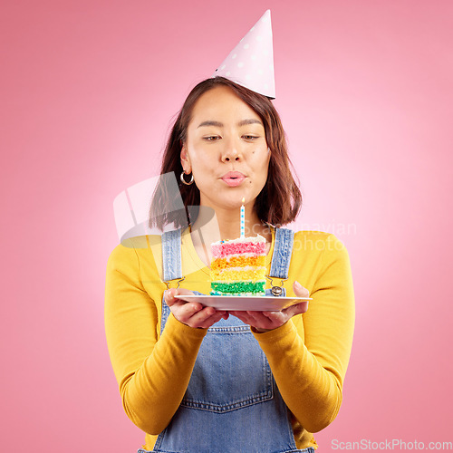 Image of Birthday cake, studio and Asian woman blow candle, fire or flame for celebration party, present or event gift. Congratulations, wish and Japanese person with dessert, candy or food on pink background