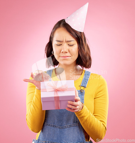 Image of Birthday present, studio box and Asian woman stress over package, ribbon opening fail or party event. Problem, bad gift mistake and Japanese person with doubt, unsure or sad on pink background