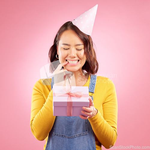 Image of Birthday present, box and curious Asian woman excited, smile and celebrate party, studio prize or gift. Secret surprise, wonder and Japanese person with mystery event package on pink background