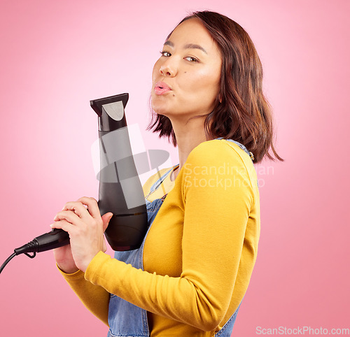 Image of Hairdryer, salon and funny with portrait of woman in studio for hairdresser, beauty and cosmetics. Shampoo, hair care and hairstyle with face of asian person on pink background for product and gun