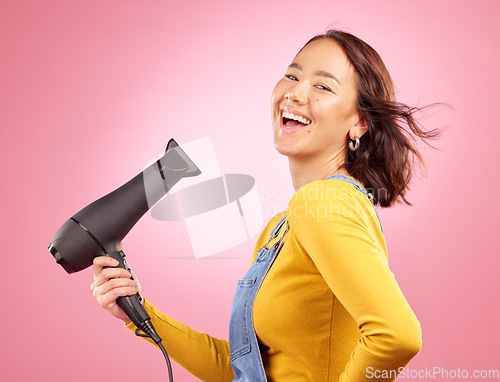 Image of Wind, salon and hair care with woman and hairdryer in studio for hairdresser, beauty and cosmetics. Shampoo, smile and hairstyle with portrait of asian person on pink background for product and spa