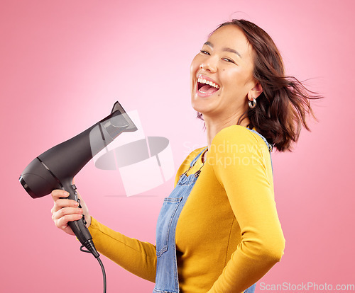 Image of Hairdryer, funny and hair care with portrait of woman in studio for hairdresser, beauty and cosmetics. Shampoo, smile and hairstyle with asian person laughing on pink background for product and salon