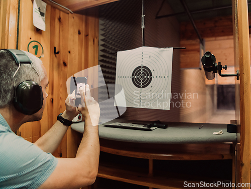 Image of A man in a shooting range takes a picture and examines the results after shooting