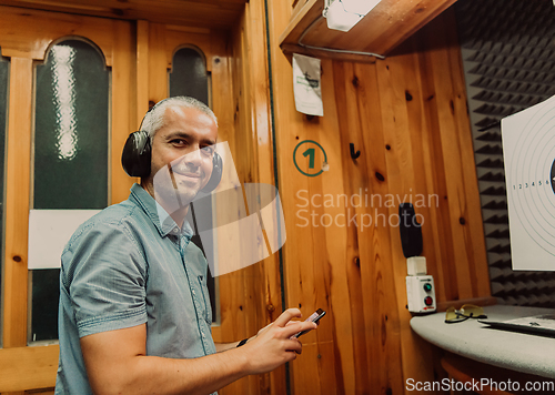 Image of A man in a shooting range takes a picture and examines the results after shooting