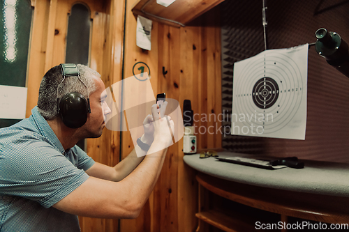 Image of A man in a shooting range takes a picture and examines the results after shooting