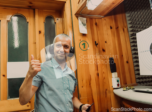 Image of A man in a shooting range takes a picture and examines the results after shooting