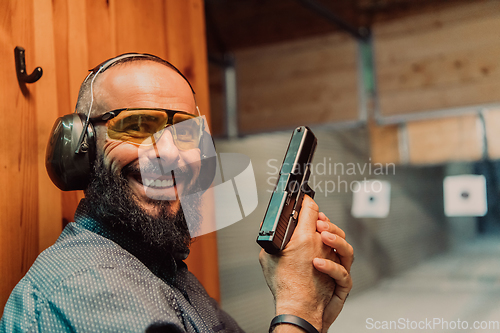 Image of A man practices shooting a pistol in a shooting range while wearing protective headphones